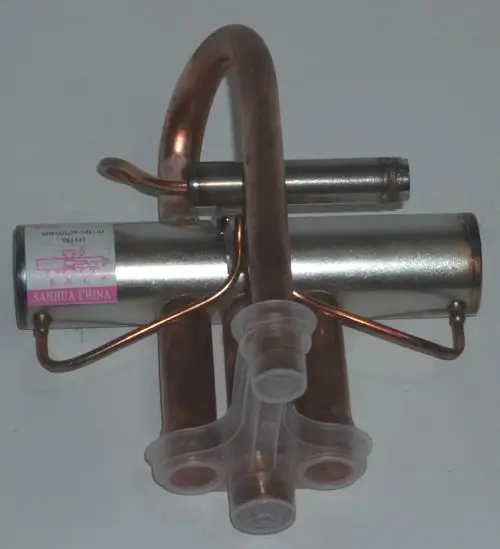 Kupfer- und Metallkomponenten eines Ventilkörpers, der Teil eines 4-Wege-Ventils von Daikin sein könnte, mit angeschlossenen Rohren und Verbindungselementen.